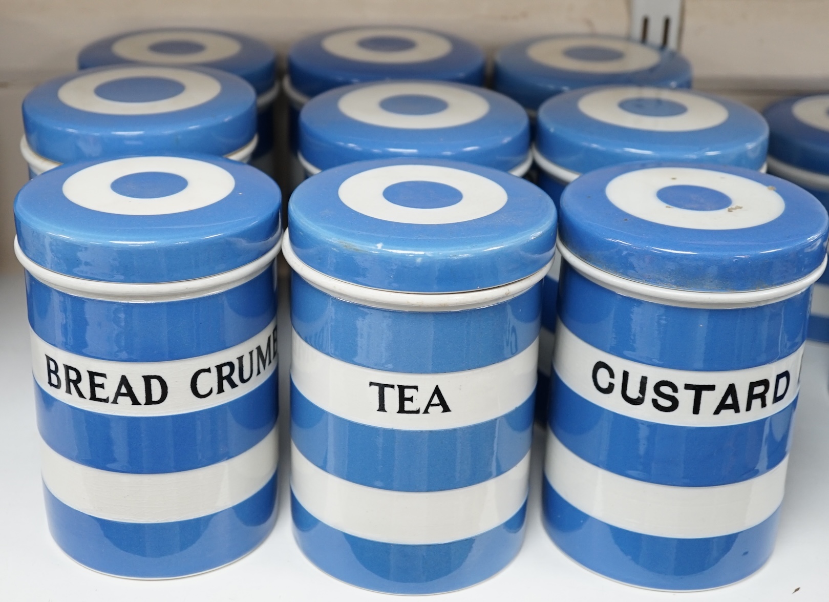 T.G.Green Cornish Kitchenware, nine 14cm lidded storage jars to include Custard Powder, Sago, Tapioca, Brown Sugar, Bread Crumbs and Prunes, Black Shield marks. Condition - fair to good